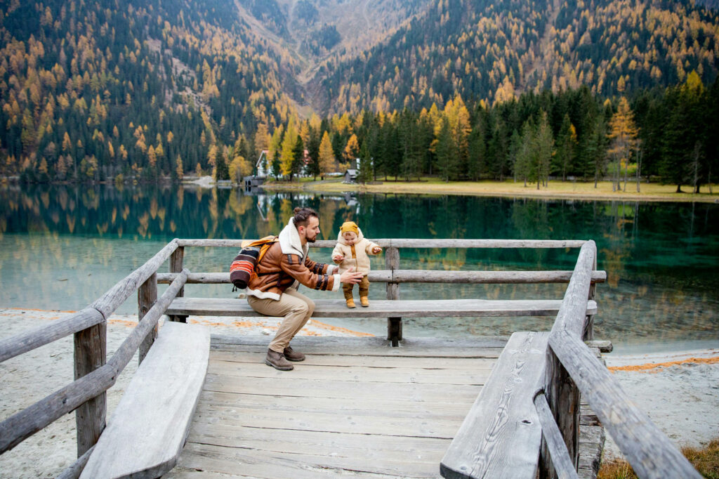 father and daughter by mountain lake in fall