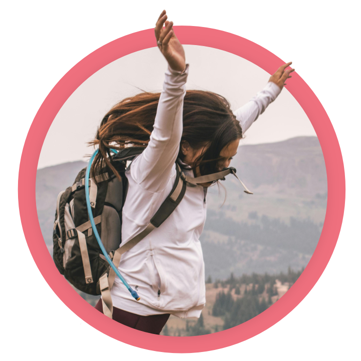 Younger girl with arms joyfully in the air, outside in the mountains