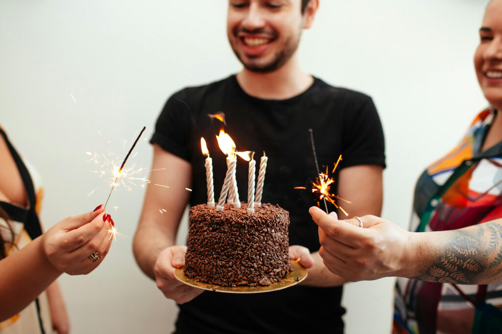 Person holding cake with candles and sparklers